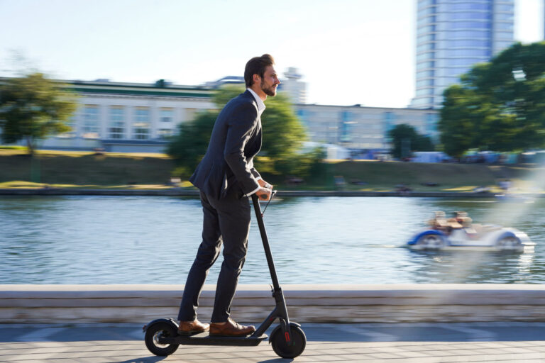 guy wearing busniess suit and riding an electric scooter